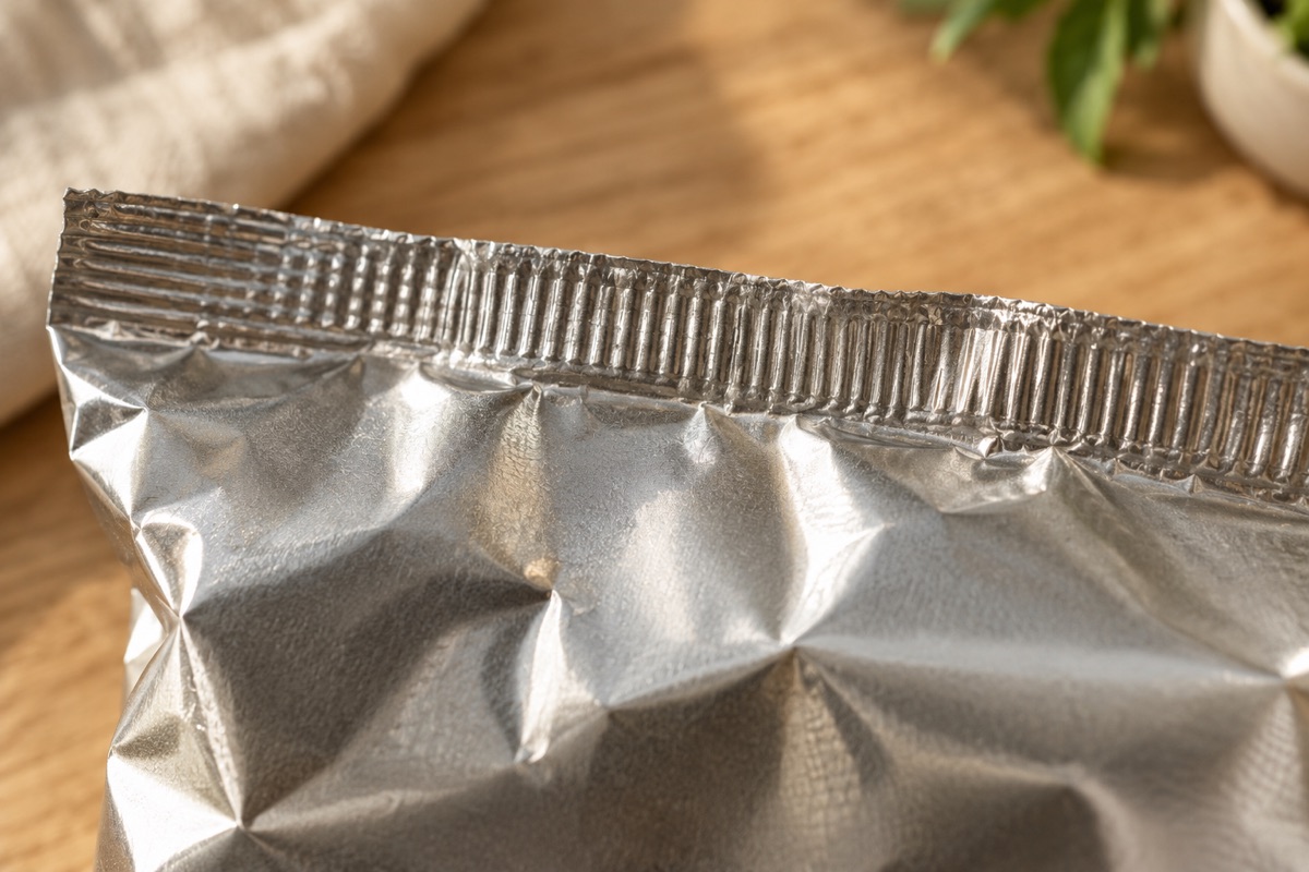 Macro view of the ridged crimped heat-sealed top edge of a silver chip bag